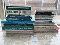 Two stacks of Newfoundland themed books on a marble surface with a window background