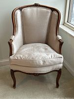 Front view of the carved Bergère armchair showing wooden frame and upholstered seat and back.