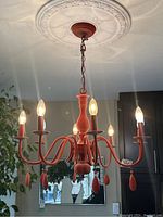 Front view of chandelier illuminated, showing overall structure, finish, and ceiling medallion