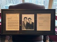 Entire framed lot displayed upright showing both contract pages and central photograph
