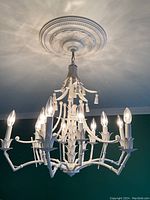 White faux bamboo chandelier hanging from ceiling, showing full fixture and decorative canopy.