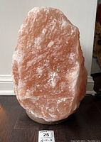 Front view of a large pink Himalayan salt lamp on a wooden base showing crystalline texture and natural salt formation.