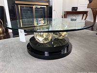 Front view of round glass coffee table showing base and three lucite balls