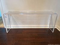 Full front view of clear lucite console table against wall