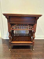 Front view showing fretwork apron, turned legs and lower shelf