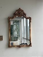 Frontal view of the gilt framed mirror hanging on wall