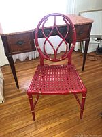 Front view of red faux bamboo and cane chair in room.