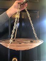 Front view of the frosted glass chandelier showing the metal hanging chain and the underside of the glass shade with dragonfly motifs.