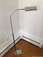 Full view of the floor lamp showing square powder-coated base, chrome pole and curved arm with attached cylindrical shade.