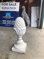 Full front view of white pineapple finial with background signage