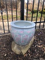 Front and angled view of vintage Chinese style porcelain planter on rock base outdoors, showing floral designs and wide rim.