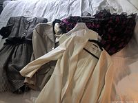 Overview of all garments including two dresses and two suits laid flat