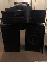 Front view of Yamaha RX-777 stereo receiver atop one speaker with both speakers visible