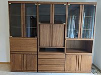 Front view of the three-piece wall unit set placed against a wall, showing all components and compartments.