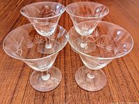 Image showing 4 dainty vintage crystal champagne glasses with etched starburst design arranged on wooden surface.