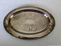 Top view of the oval silver plated serving tray showing detailed engraved interior design and mild tarnishing.