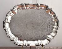 Full view of larger oval scalloped-edge silver plated tray with intricate floral and scroll engraved pattern and polished surface.