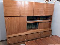 Full front view of the teak wall unit showing upper cabinets, central display and lower drawers