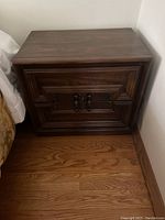 Front view of solid walnut 2-drawer nightstand showing detailed drawer fronts and handles.