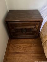 Front view of the solid walnut nightstand showing two carved drawers and dark walnut finish.
