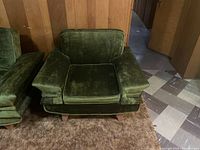 Front view of vintage green velour chair showing seating area, armrests, and cushion.