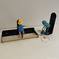 Both items shown together: paper towel holder with cyclist and separate cycling man ringing bell with pull rope