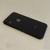 Rear angled view of black Apple iPhone showing single camera and flash