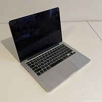 Front left angled view of MacBook Pro 13-inch laptop with screen open showing keyboard and trackpad.