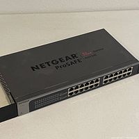Close-up angled view of the Netgear ProSafe Plus 24-Port Switch showing the top and front with ports and labels.