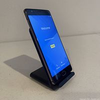 Photo of the front of the OnePlus smartphone showing the display powered on with welcome screen.