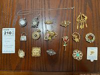 Photo of assortment of various costume jewelry brooches and pendant watches laid out on wood surface