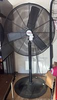 Black Central Machinery shop fan on round base with adjustable height stand, three blades inside large 32-inch diameter cage, Central Machinery logo on center hub.