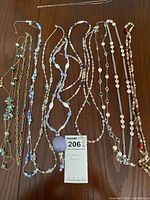 Photo of 10 costume jewelry necklaces laid out on a wooden surface showing various bead colors and chain styles.