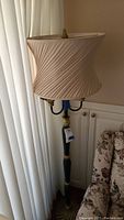 Full view of the floor lamp showing the twisted beige fabric lampshade and part of the base