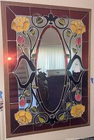 Front view of the stained glass mirror showing the stained glass floral border and oval center mirror reflecting the room