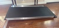 Top angled view of rectangular Gateway wheelchair ramp with aluminum raised edges and textured black surface for traction.