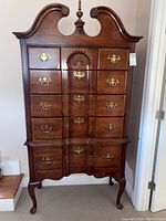 Front view showing full highboy chest with intricate drawer layout, brass hardware, and shell motif.