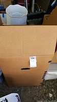 Three cardboard boxes with lamps and lamp shades packed inside, showing one white scalloped fabric lamp shade and beige woven lamp shade partly visible.