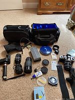 Overview of entire lot on carpet: camera, motor drive, flash, lenses, bags and accessories