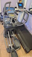 Full view of the Octane Fitness elliptical trainer next to a treadmill, showing handles, pedals, and display console.
