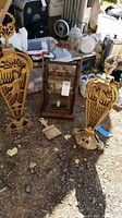 Two brass folding fire screens and wooden candle box displayed outdoors among other household items
