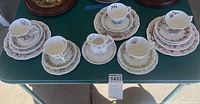 Multiple tea cups and saucers arranged on table showing variety and patterns.