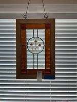 Front view of stained glass art with wooden frame, showing pressed flowers in circular clear glass center, surrounded by orange and red glass pieces and textured clear glass.