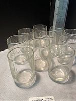 Ten vintage clear etched juice glasses arranged together
