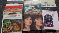 Top view of multiple vinyl record album covers arranged in a fan displaying various genres including musicals and rock.