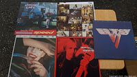Overview photo of five vinyl record albums from the 70s and 80s showing front cover art including Stray Cats, The Cars, Tom Petty, Van Halen, and an unidentified band.