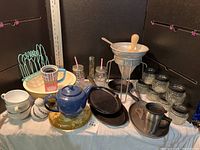 Photo showing the complete lot on a photo table with black background including cast iron skillets, Drama Momma cup, wooden bowl, candleholders, and other kitchen items.