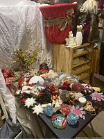 Wide view of assorted Christmas decorations spread on table, including ornaments, pine cones, berries, snowflakes, figurines, and a large red Santa stocking.