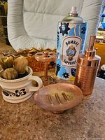 Wide view showing copper bathroom set with soap dish, toothbrush holder, tumbler, vintage shaving brushes in barbershop mug, copper ceramic planter, and Bombay Sapphire tin.