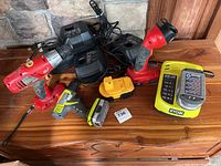 Overall view of cordless drills, chargers, and batteries on wooden surface.
